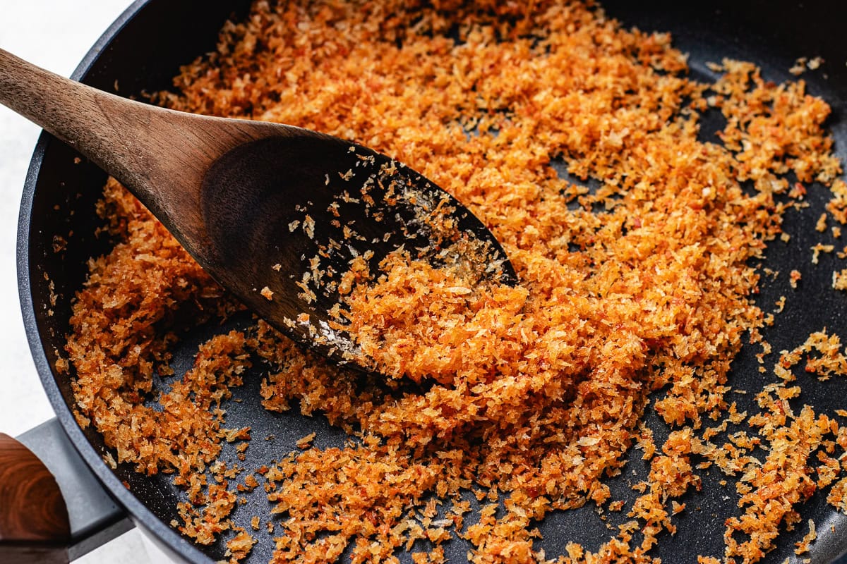 toasted garlic breadcrumbs in skillet with wooden spoon. 