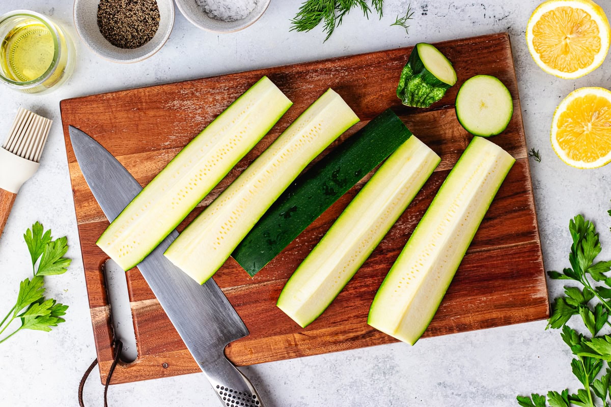 zucchini cut into spears on wood cutting board. 