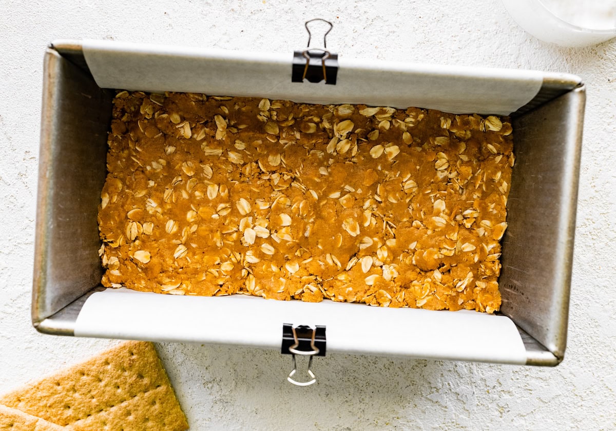 peanut butter layer pressed in loaf pan to make no bake peanut butter s'mores bars. 