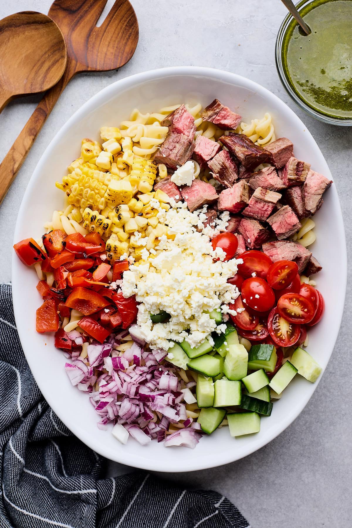 steak pasta salad ingredients in large white bowl. 