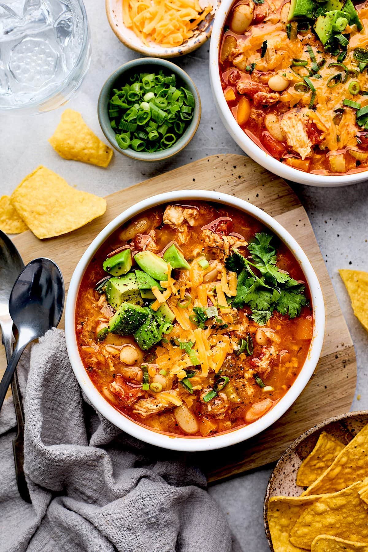 buffalo chicken chili in bowl with cheese, avocado, and cilantro. 