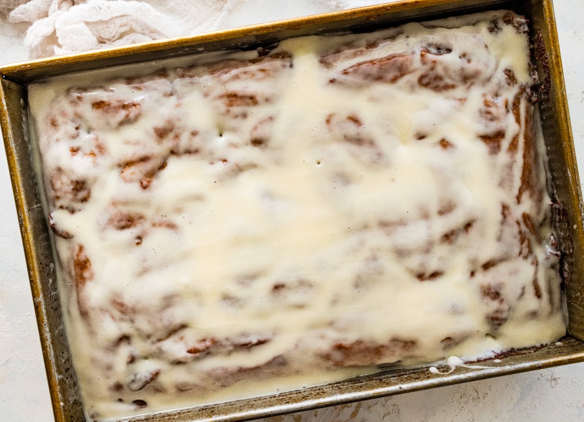 cream cheese icing spread over pumpkin cake in pan. 