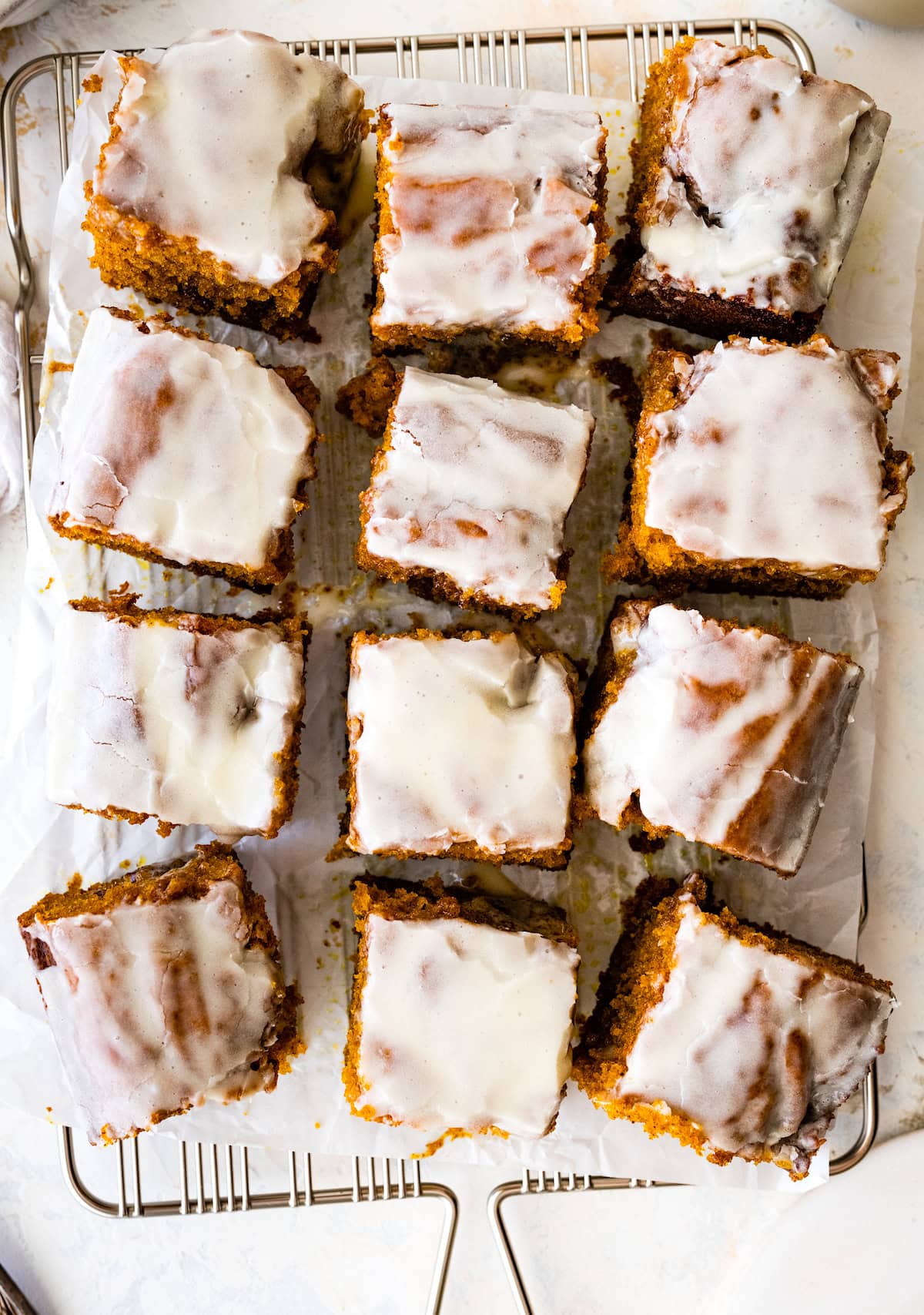 pieces of cinnamon swirl pumpkin cake with cream cheese glaze on cooling rack. 