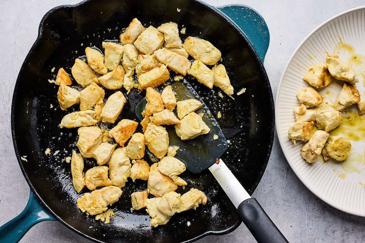 cooked chopped up chicken in cast iron skillet with spatula. 