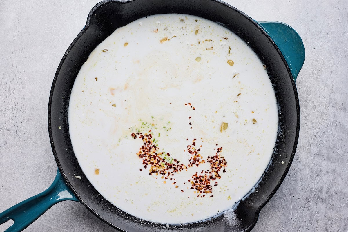 coconut milk sauce with spices cooking in cast iron skillet. 