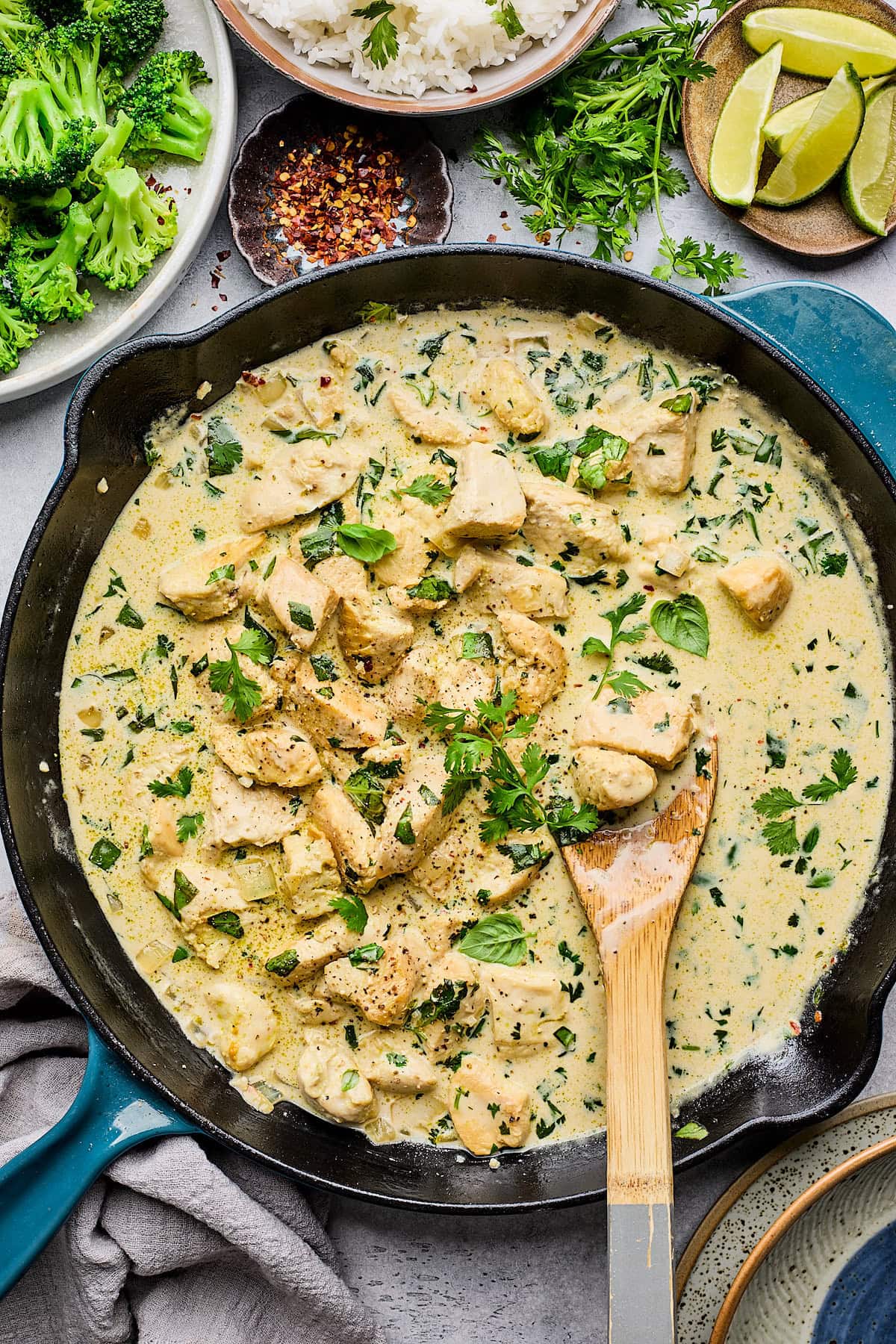 coconut lime chicken in cast iron skillet with wooden spoon. 