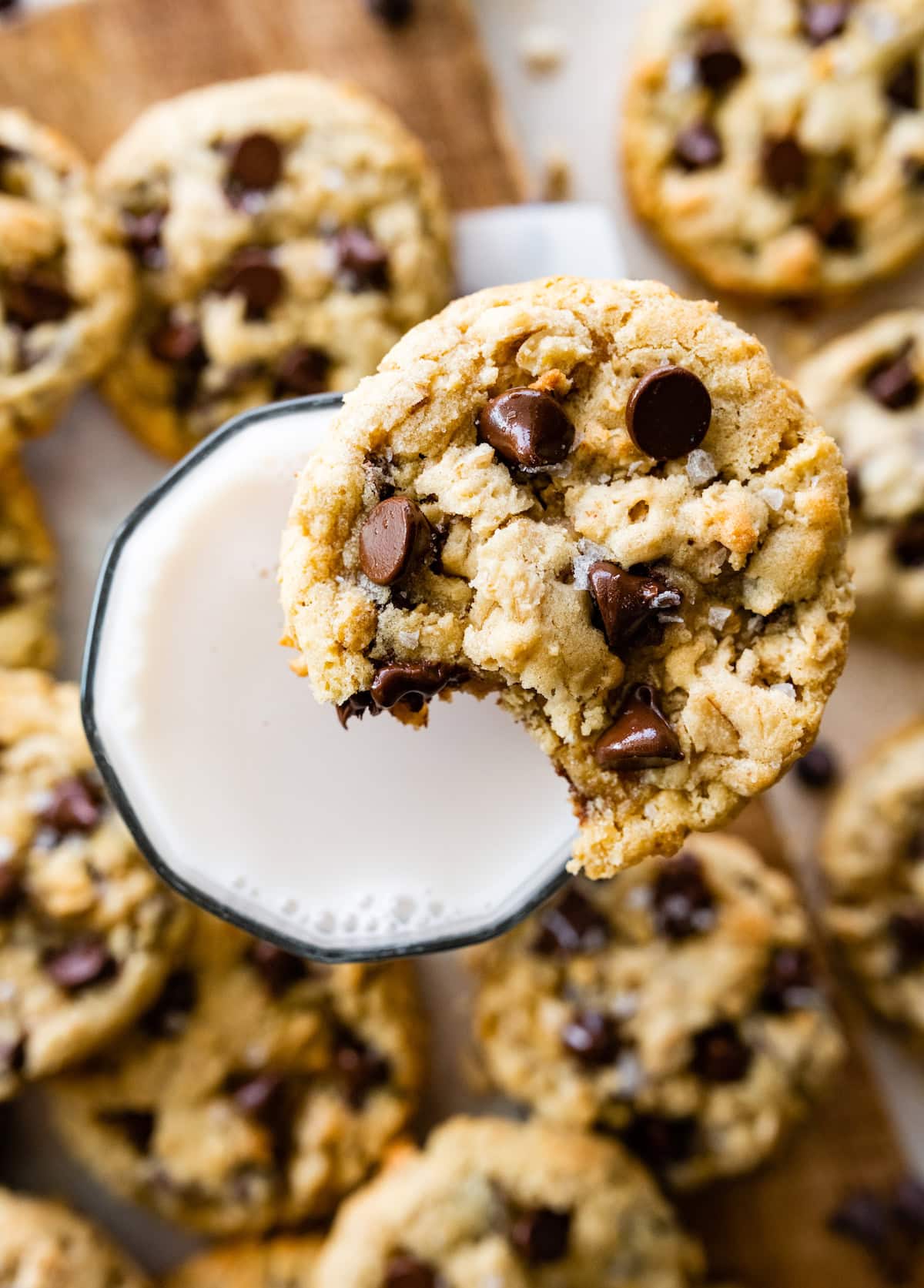 oatmeal chocolate chip cookie with a bite taken out and glass of milk. 