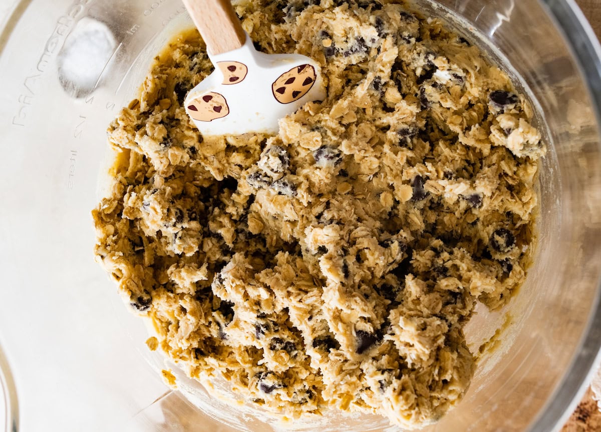 oatmeal chocolate chip cookie dough in mixing bowl with spatula. 