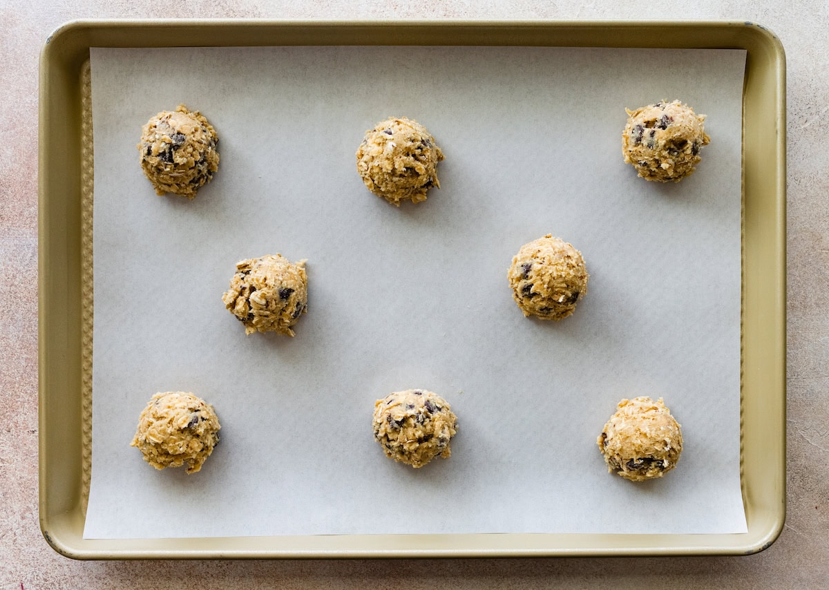 oatmeal chocolate chip cookie dough balls on baking sheet with parchment paper. 