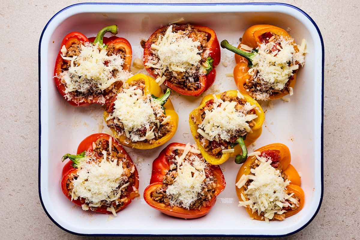 stuffed peppers in pan with meat mixture and shredded cheese ready to go in oven. 