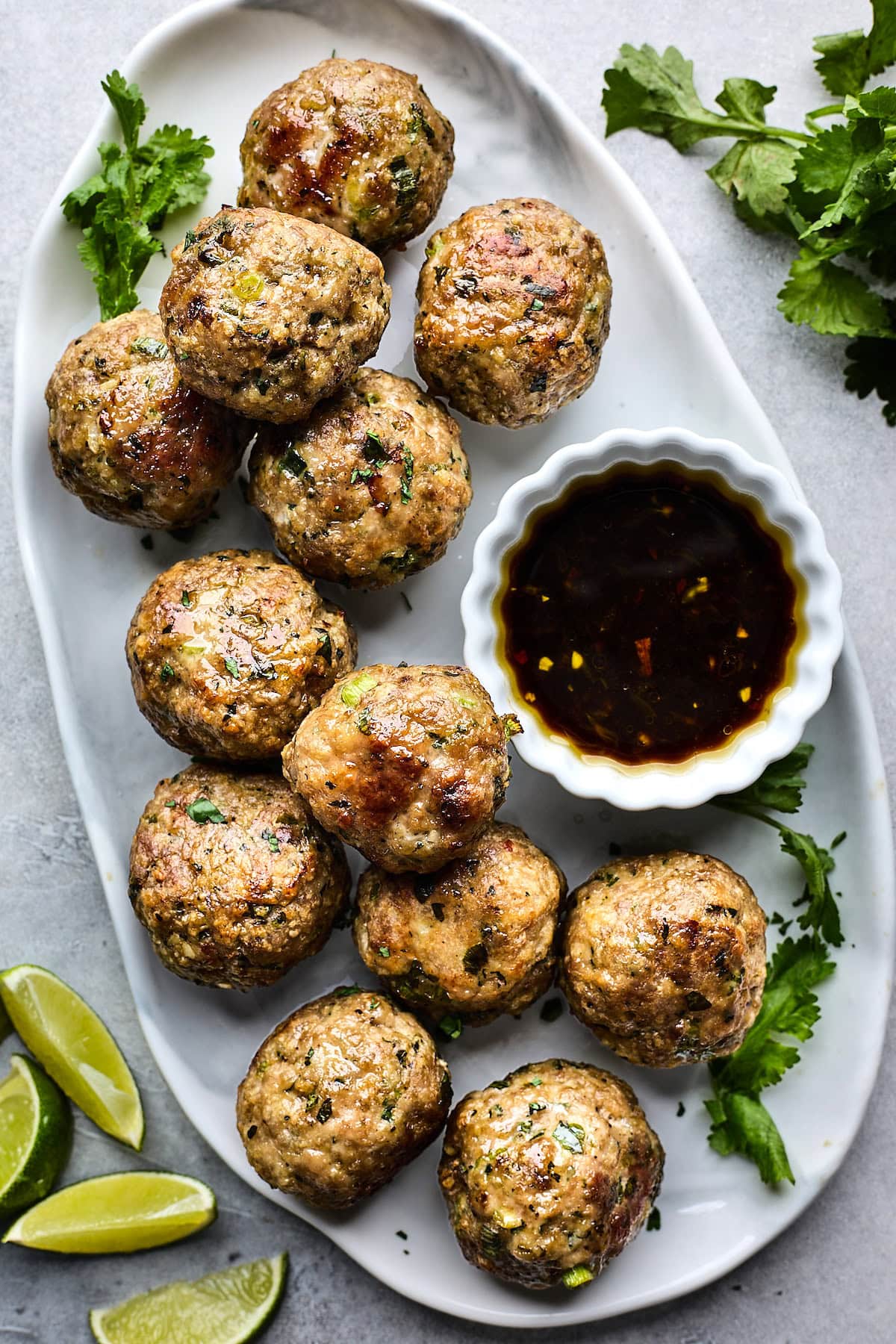 Asian meatballs on platter with bowl of soy ginger dressing. 