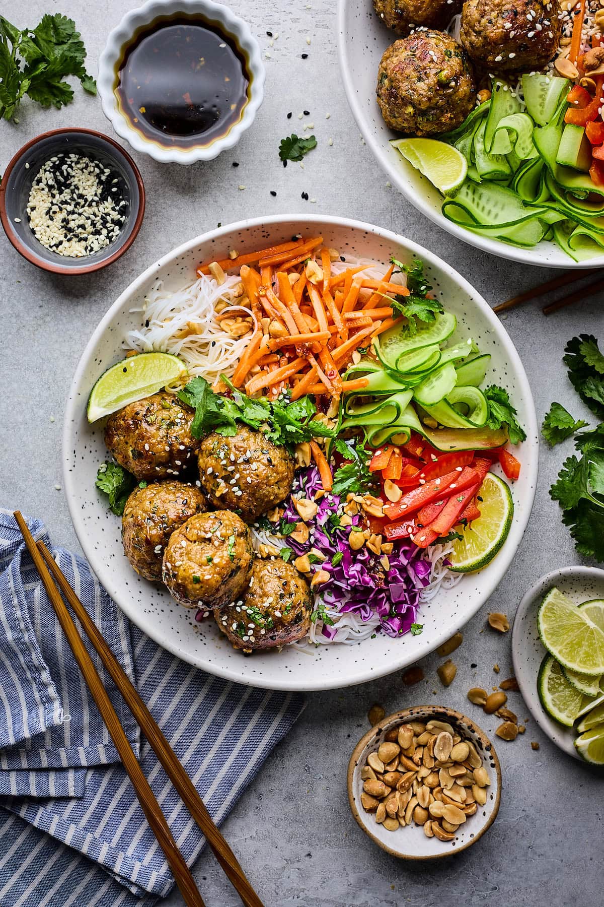 Asian-inspired noodle bowls with soy ginger meatballs, noodles, fresh vegetables, peanuts, herbs, and lime wedges. 