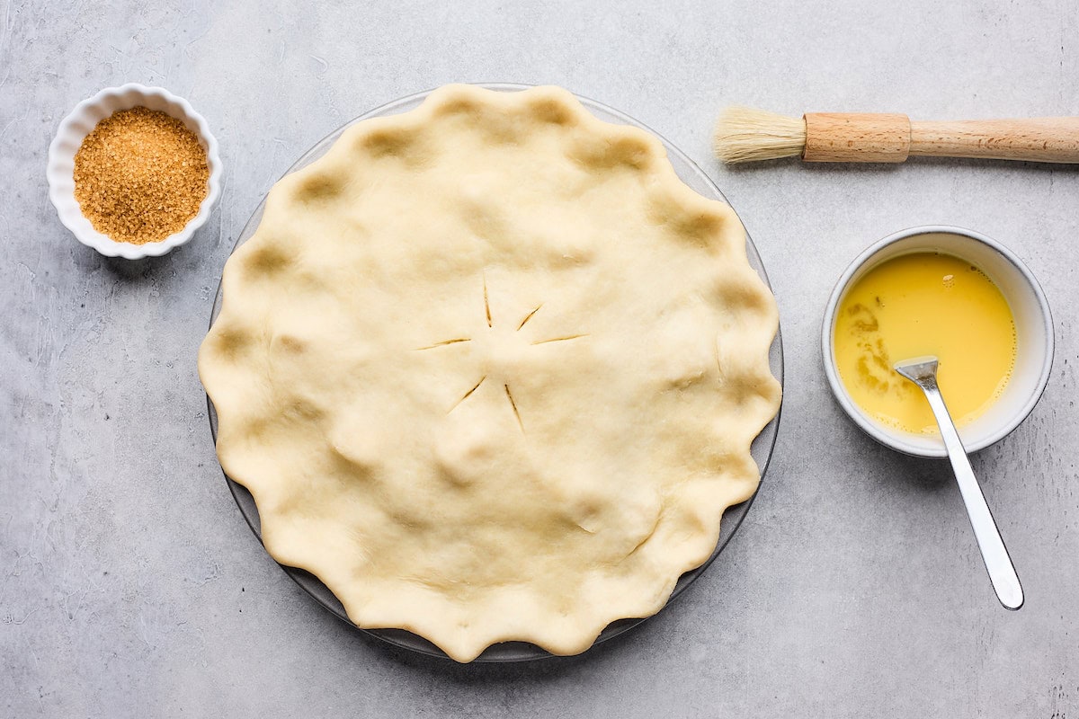 apple pie with pie dough crimped on top, ready for an egg wash. 