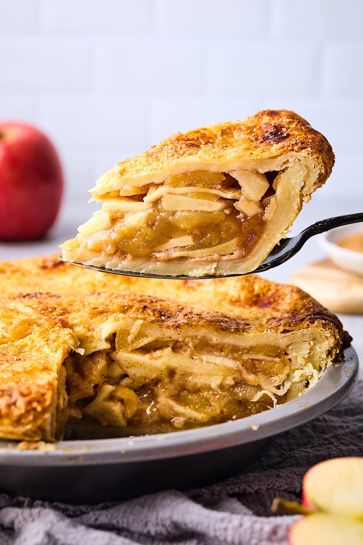 a slice of apple pie being lifted out of the pie pan. 