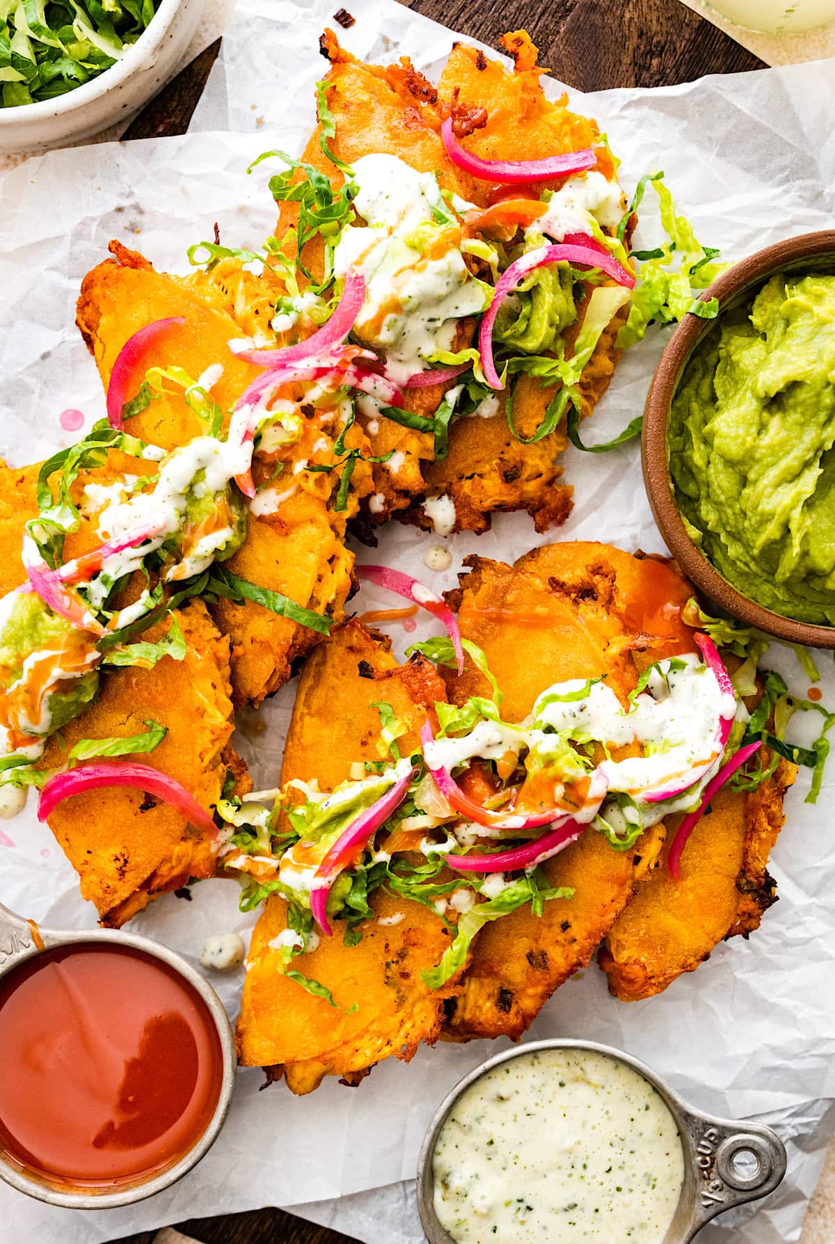 crispy buffalo chicken tacos with pickled red onions, guacamole, lettuce, and crema. 