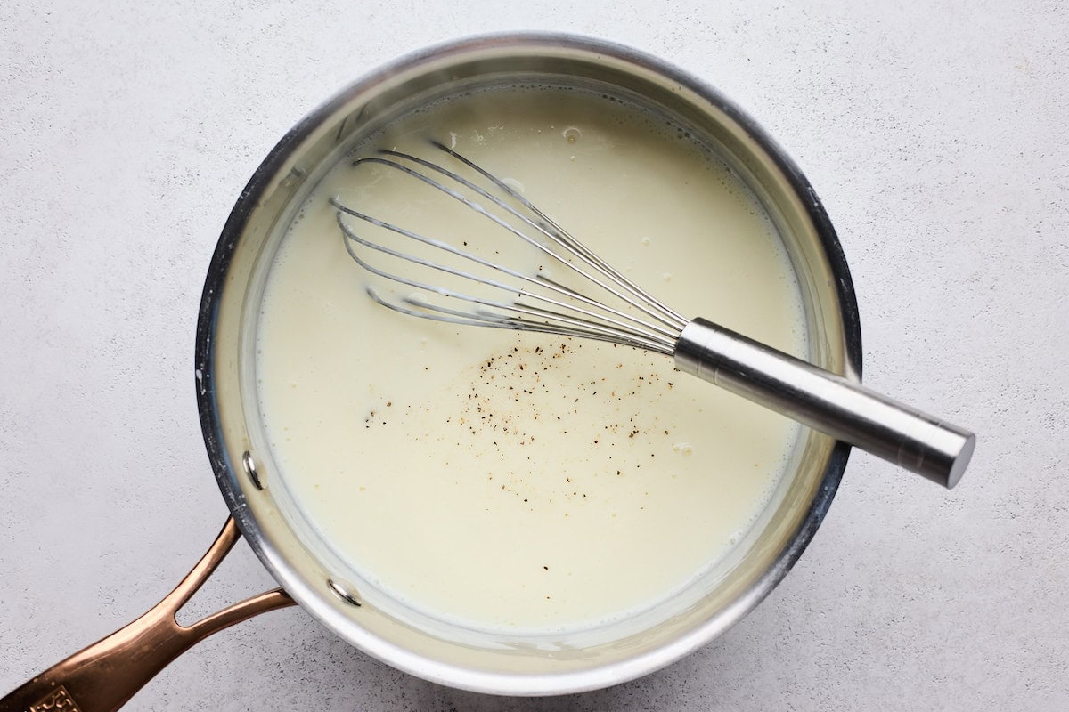 bechamel sauce in saucepan with whisk to make butternut squash lasagna. 