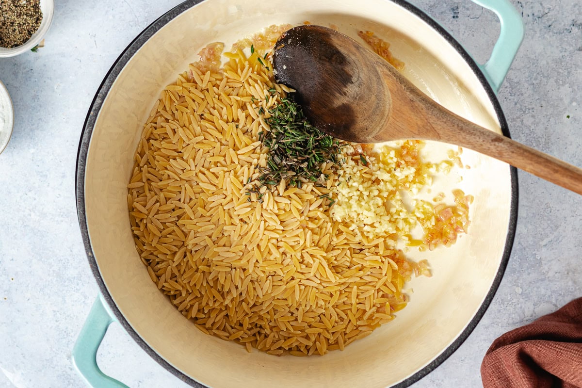 orzo toasting in pot with herbs and garlic. 