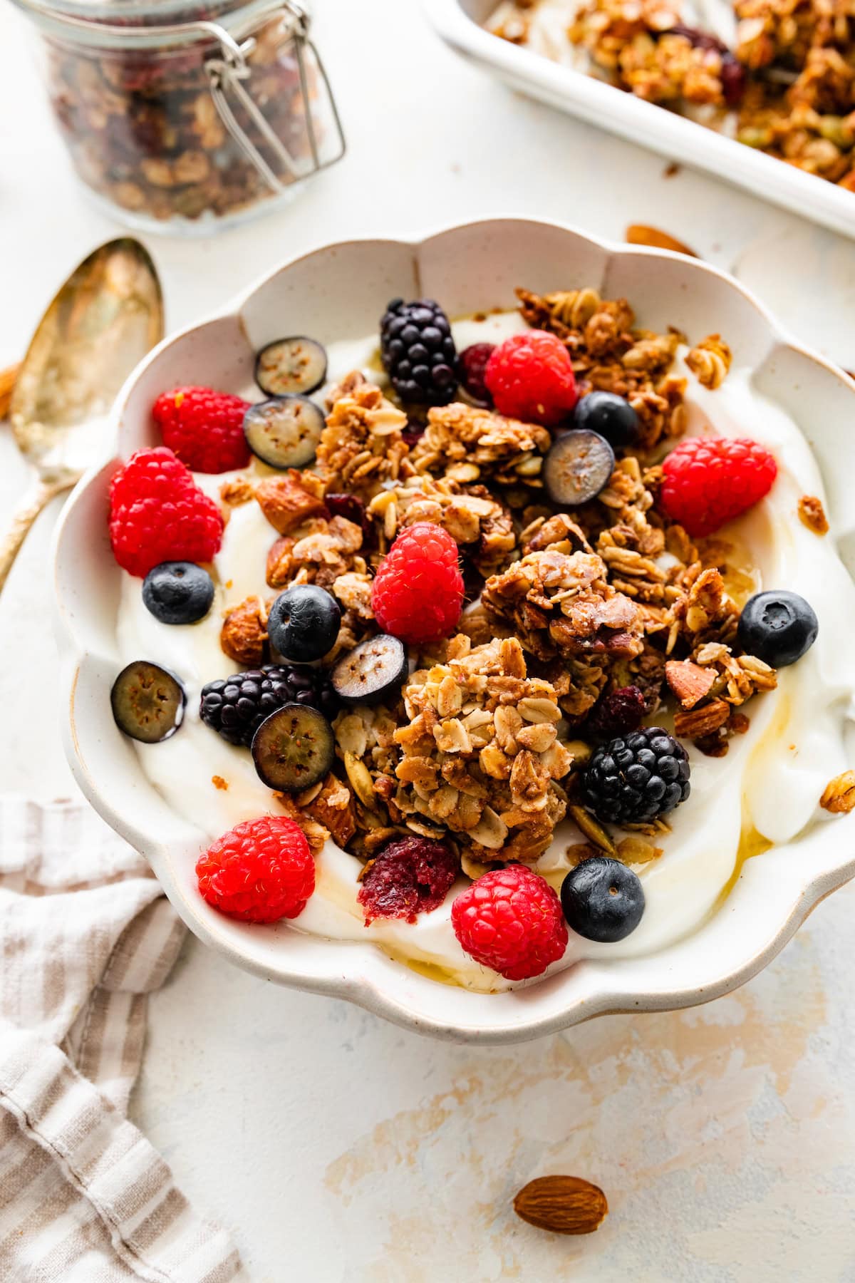 yogurt in a bowl with berries, homemade granola, and honey. 