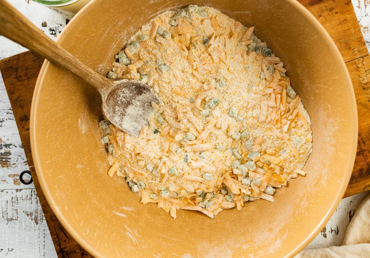 shredded cheddar cheese and diced jalapeños being mixed into dry ingredients to make jalapeño cheddar cornbread. 