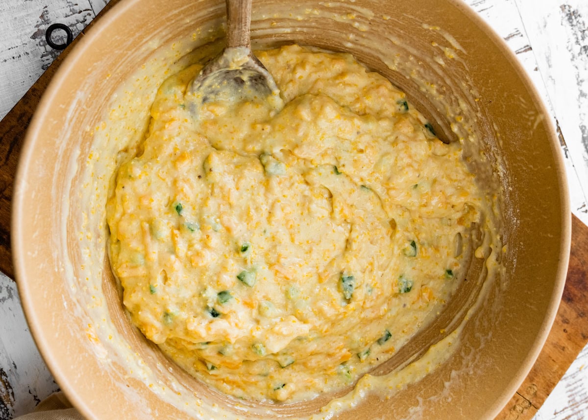 jalapeño cheddar cornbread batter in mixing bowl with wooden spoon. 