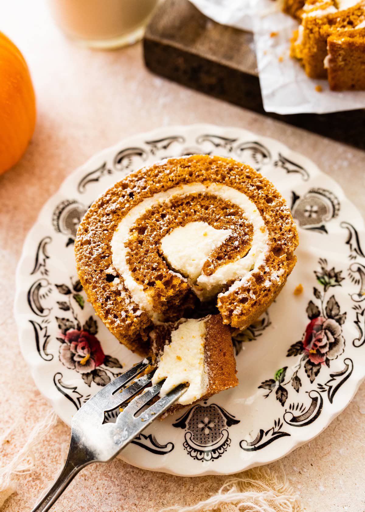 piece of pumpkin roll cake on plate with fork. 