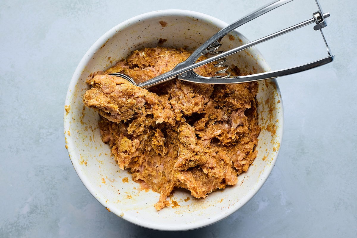 tikka masala meatball mixture in bowl with scoop. 