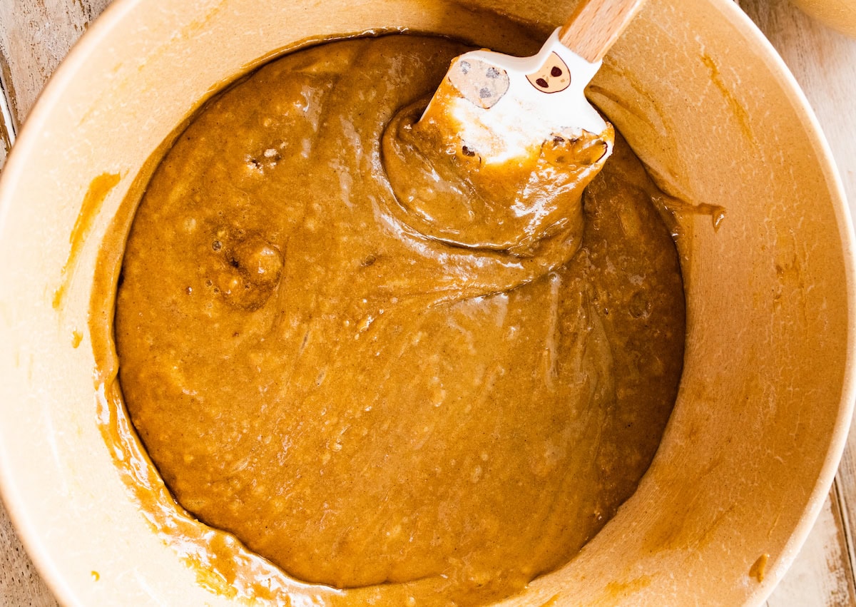 apple cake batter in mixing bowl with spatula. 