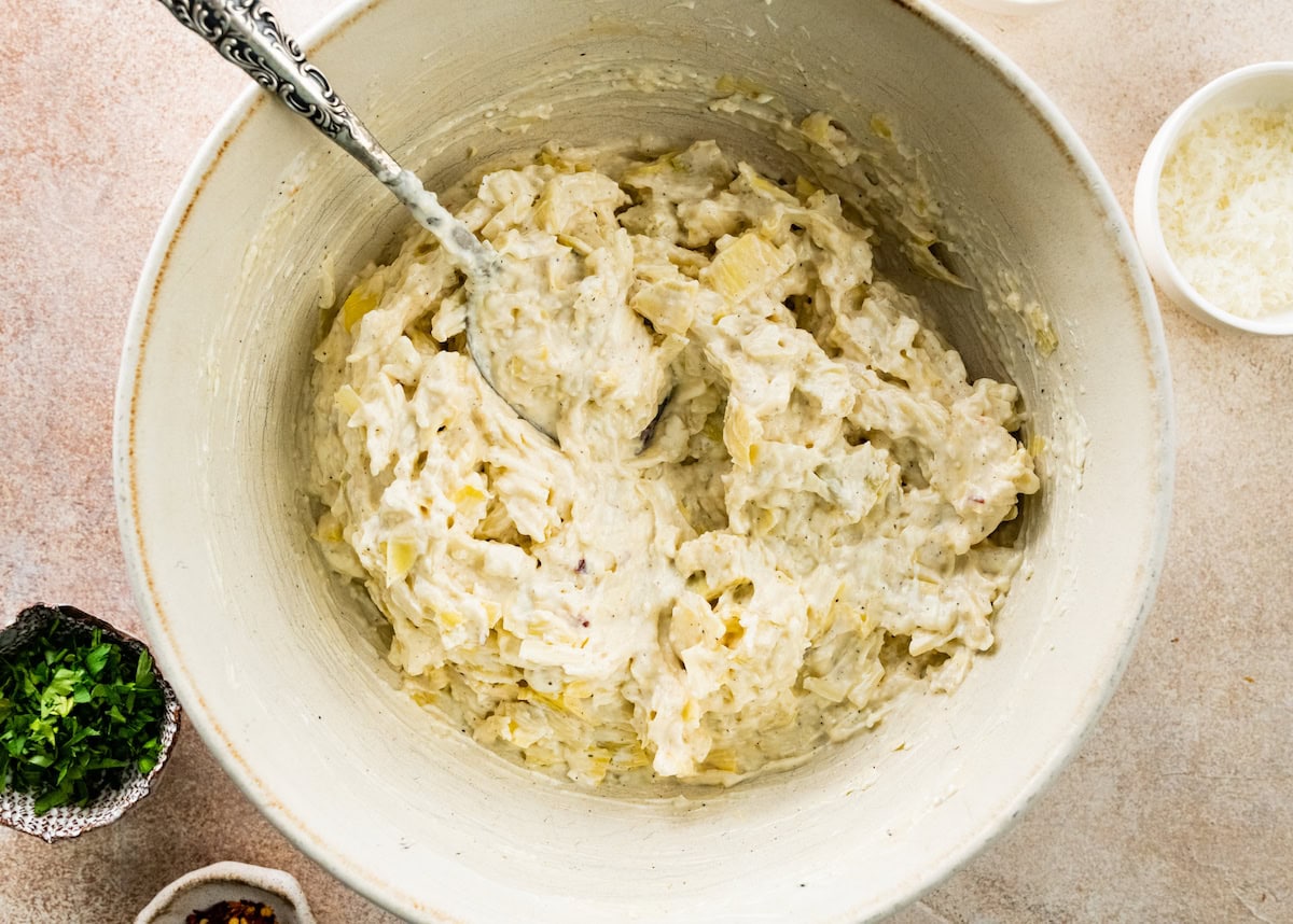 artichoke dip in mixing bowl with spoon. 