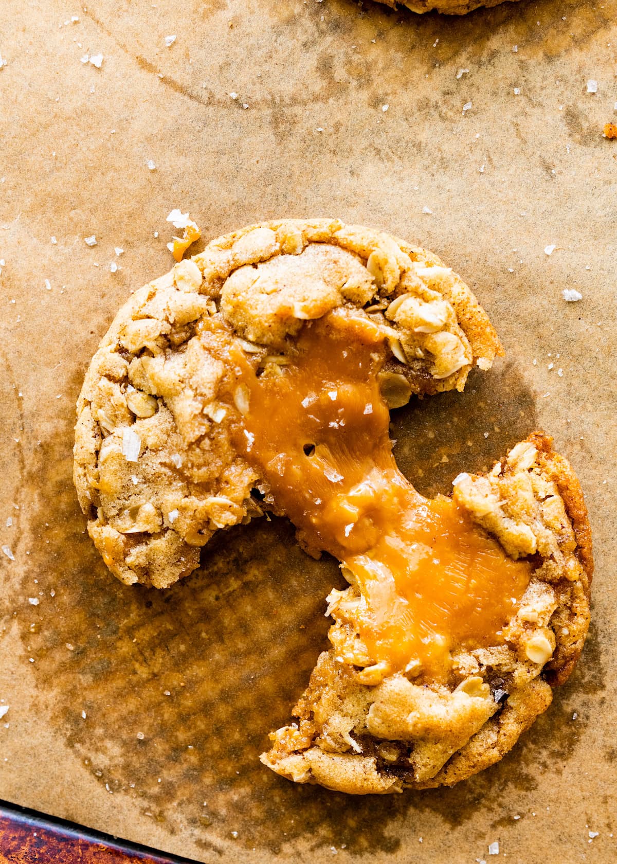 brown butter caramel oatmeal cookie broken in half with a caramel pull. 