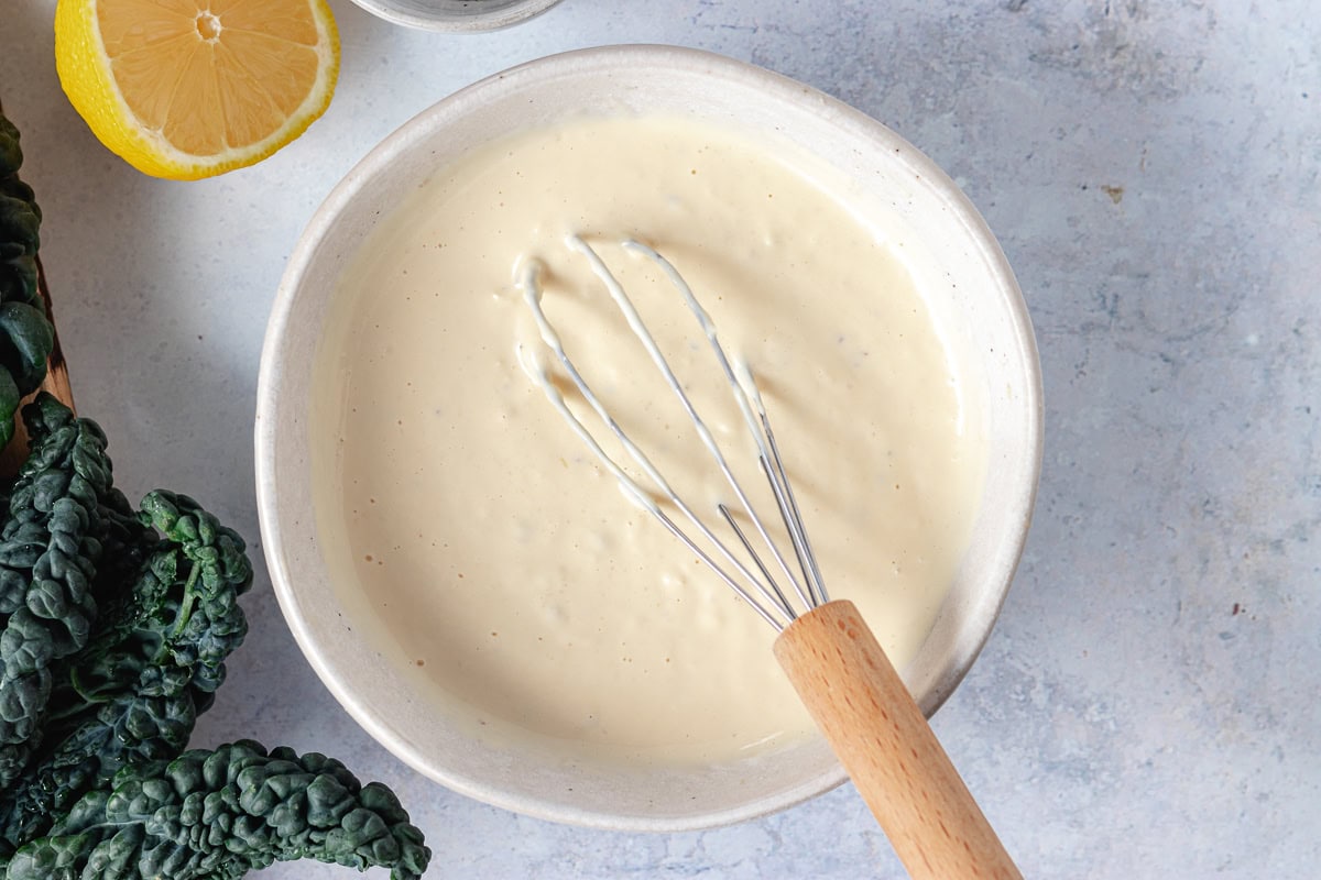 caesar dressing in bowl with whisk. 