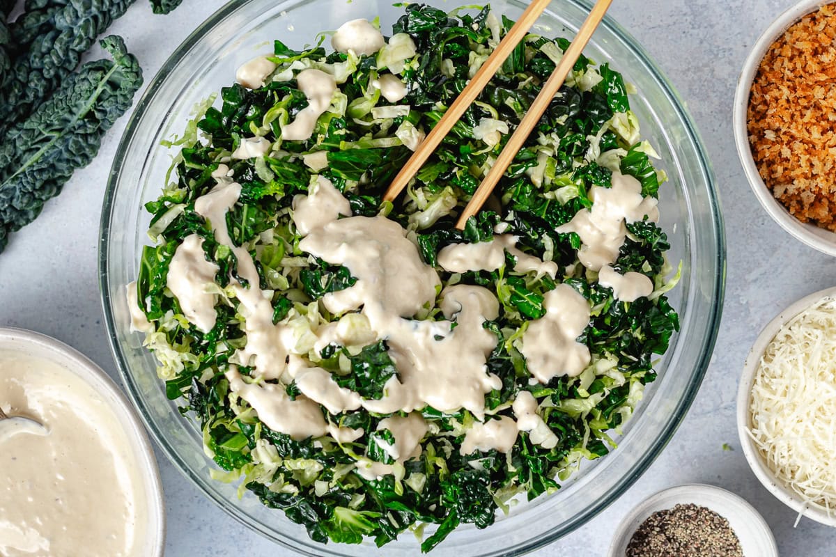 shredded Brussels Sprouts and kale in bowl with Caesar dressing. 