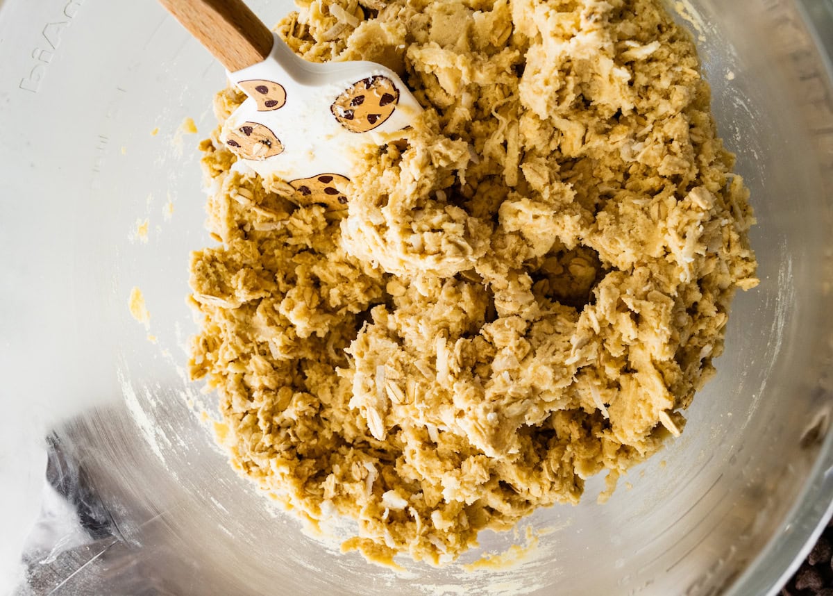 oatmeal coconut cookie dough in mixing bowl with spatula. 