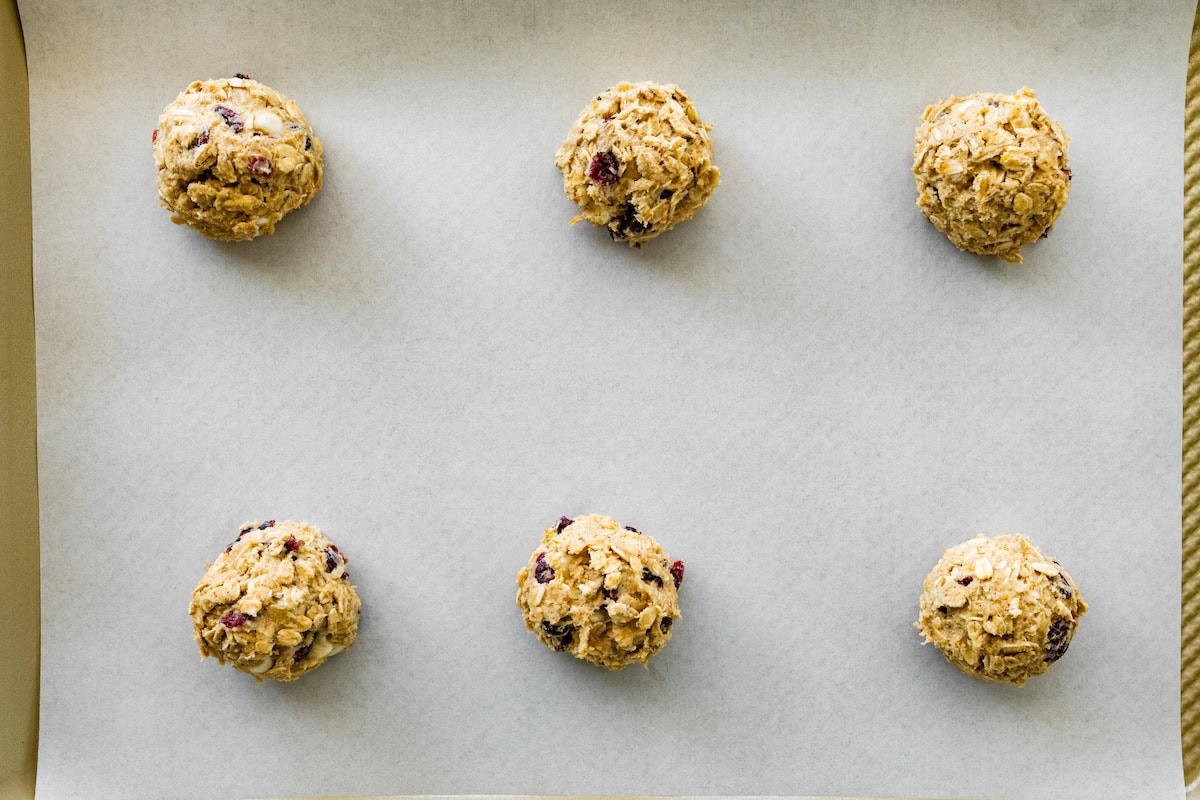 cranberry orange white chocolate oatmeal cookie dough balls on baking sheet with parchment paper. 