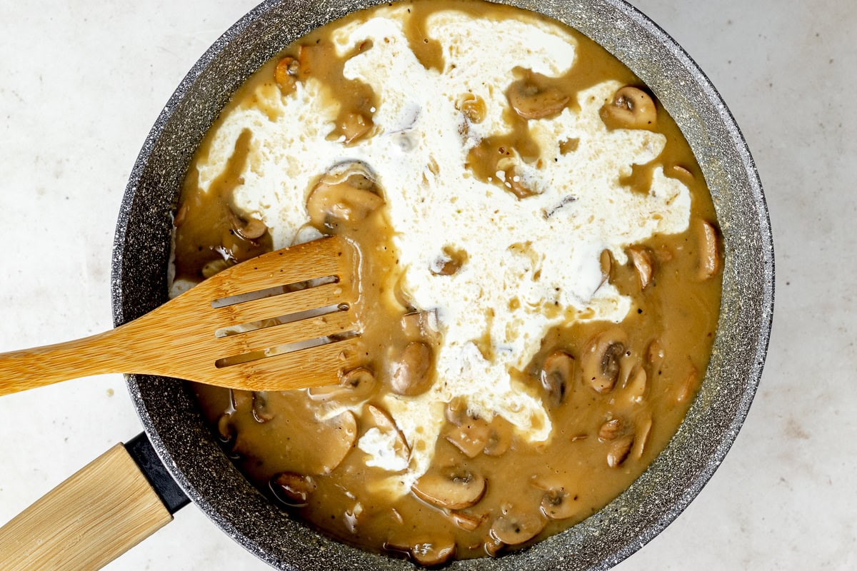 mushroom cream sauce cooking in skillet to make green bean casserole. 