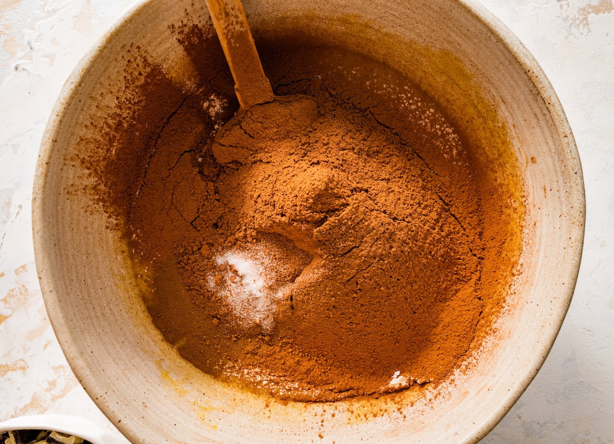 cocoa powder being sifted into brownie better in mixing bowl with spatula. 