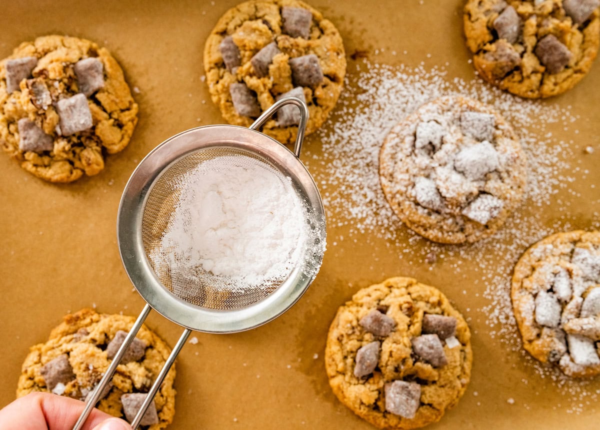 confectioner's sugar being sifted over puppy chow cookies. 