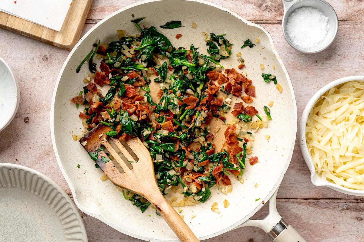 spinach, bacon, onion, and garlic cooking in skillet. 