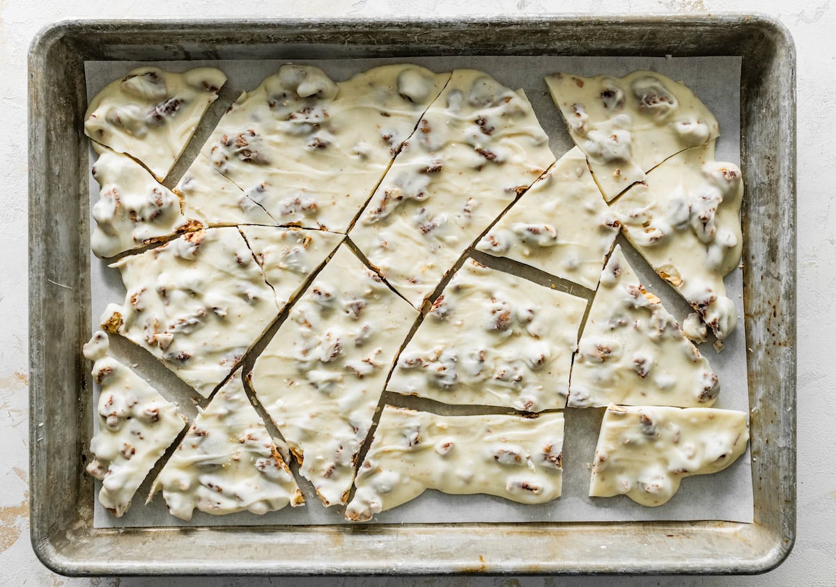 white chocolate candied pecan bark broken into pieces on baking sheet. 