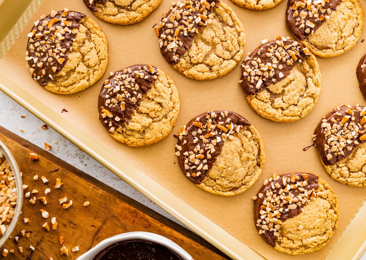 chocolate dipped pretzel cookies on baking sheet with parchment paper. 