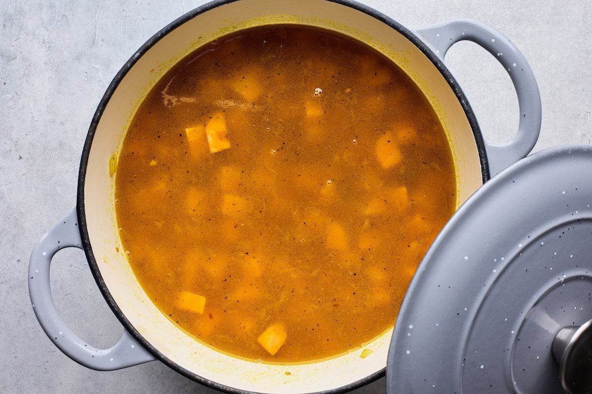 broth added to Creamy Coconut Ginger Sweet Potato Soup in pot. with lid. 