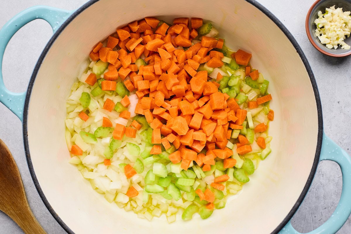 onion, carrot, and celery cooking in pot to make Italian wedding soup. 