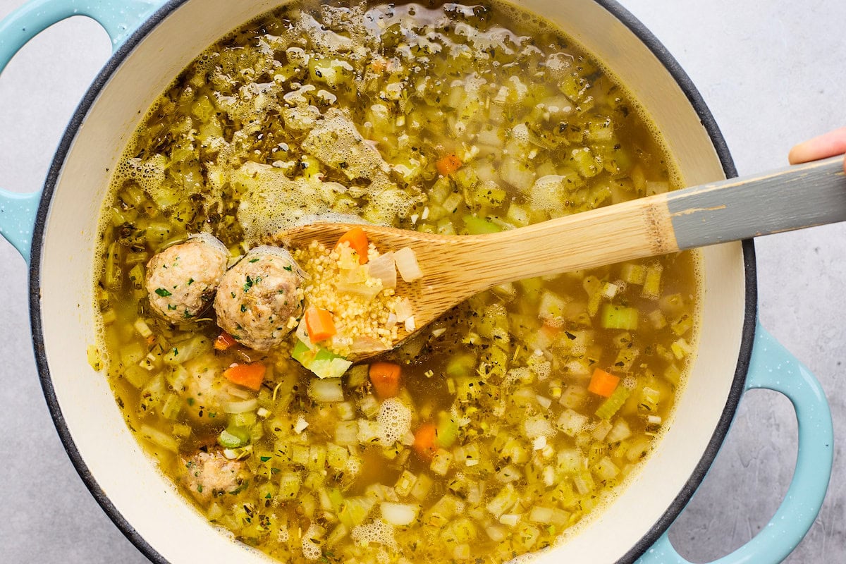 meatballs cooking in broth in large pot to make Italian wedding soup. 