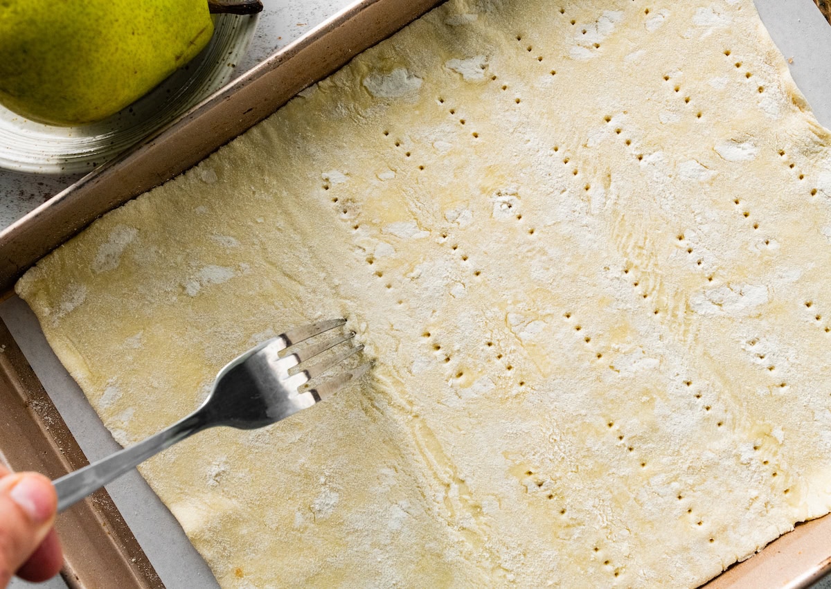 puff pastry being pierced with a fork all over. 