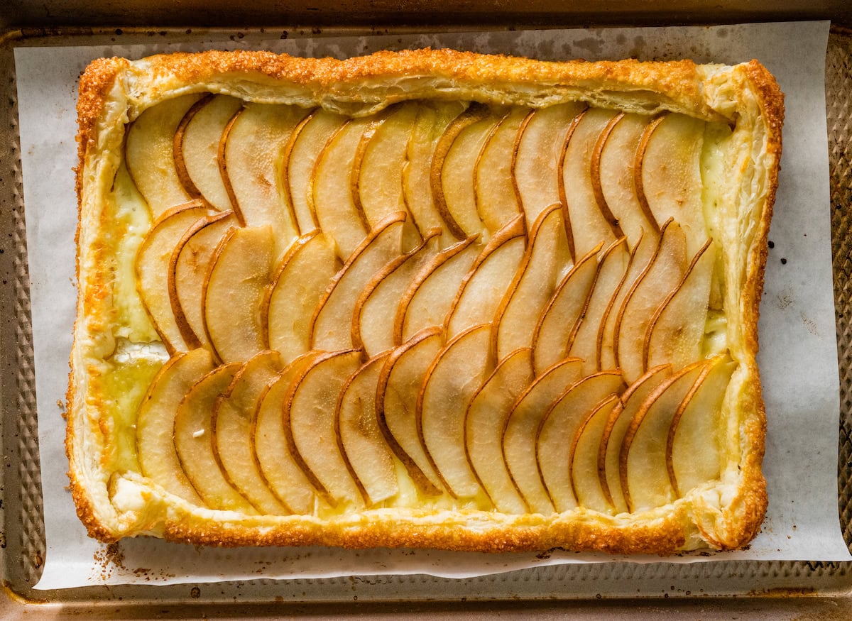 pear brie puff pastry tart on baking sheet. 