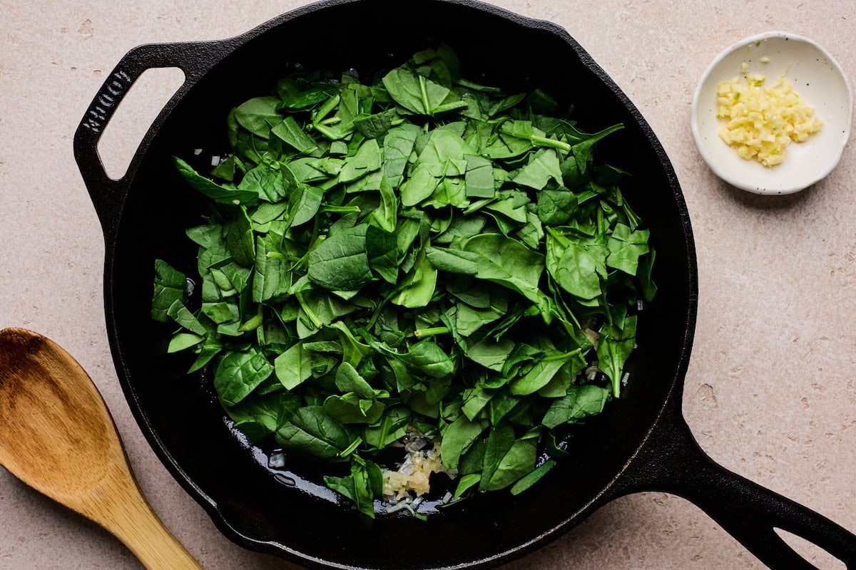 spinach and shallot cooking in cast iron skillet. 