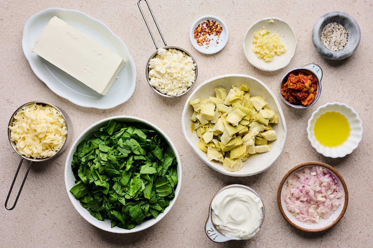 ingredients in bowls to make spinach artichoke sun-dried tomato dip. 