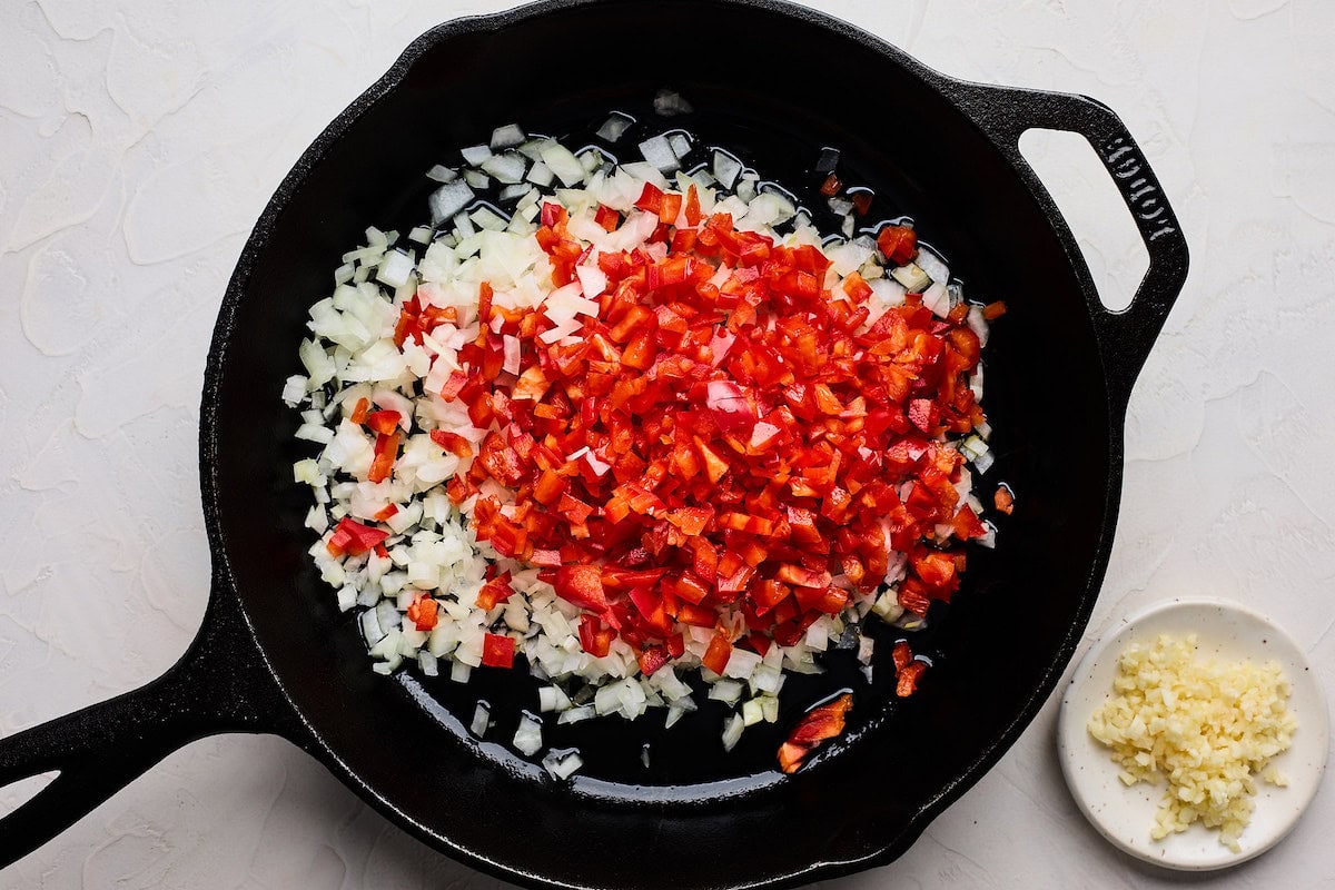 onion and red peppers cooking in cast iron skillet with garlic to make black bean burger. 