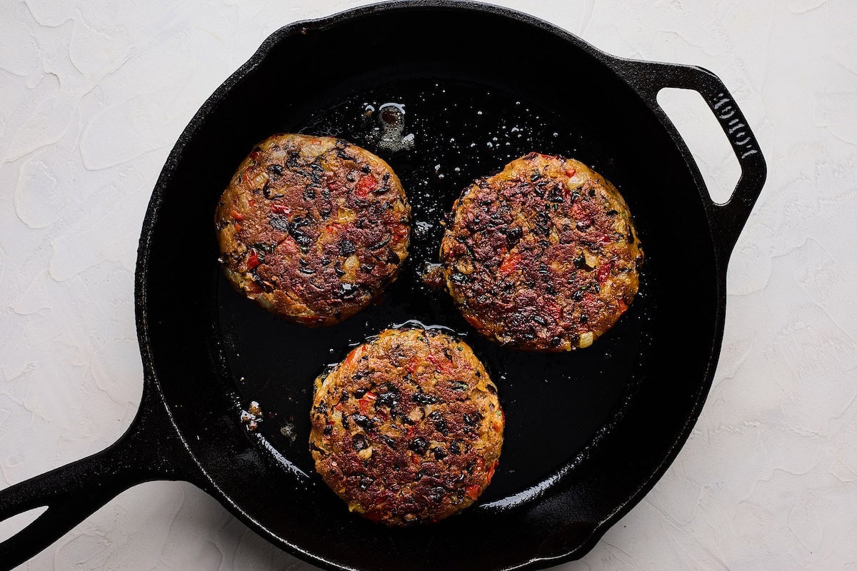 black bean burgers cooking in cast iron skillet. 