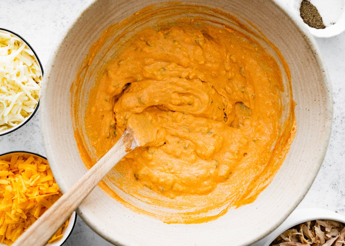 buffalo chicken dip mixture being stirred together in mixing bowl. 