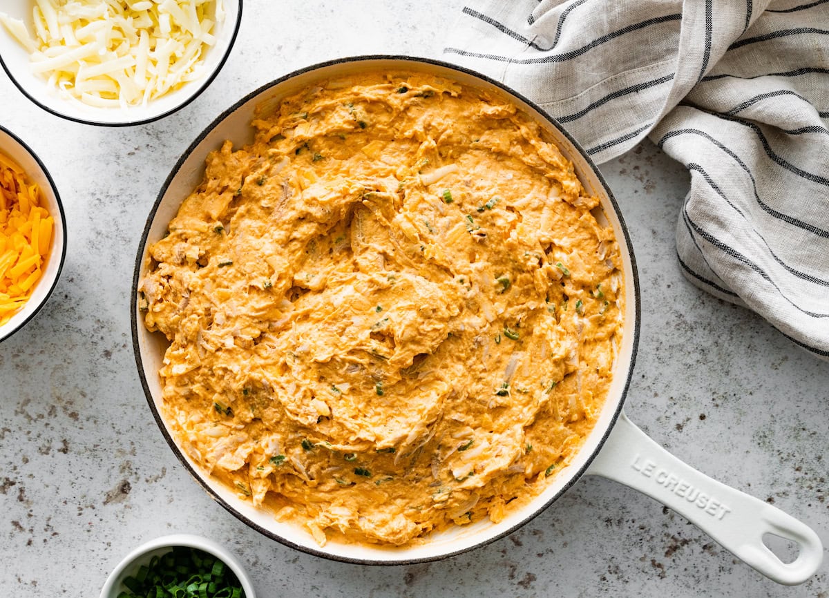 buffalo chicken dip mixture spread into skillet ready to be topped with cheese. 